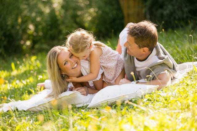 Rodzina trzosobowa odpoczywająca latem na trawie